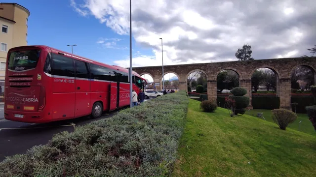 Autocar rojo de Autocares Cabria junto a un puente de piedra